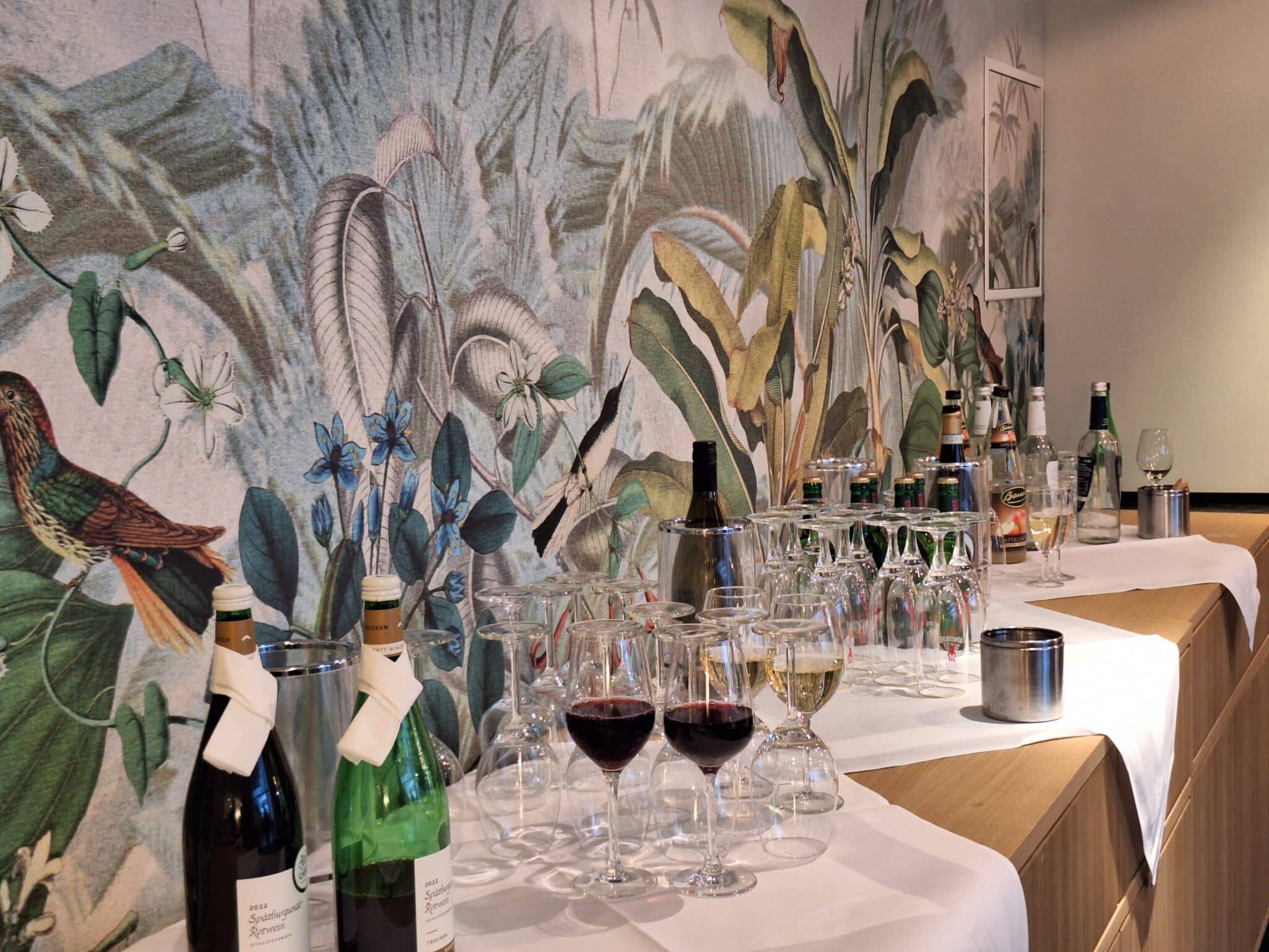 Eine Getränkebar mit verschiedenen Flaschen und Gläsern auf einem Tisch in einem Innenraum.