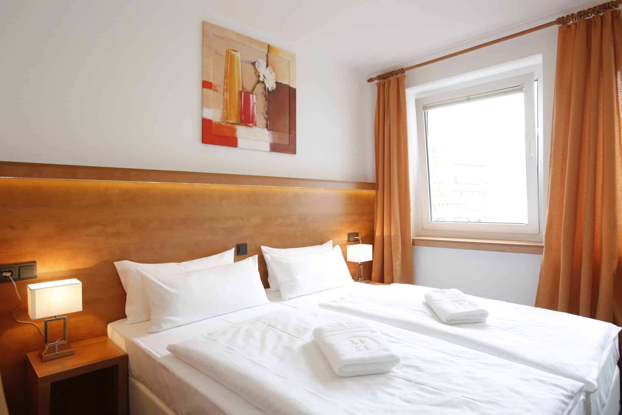 Ein Doppelzimmer mit zwei Betten, weißen Bettlaken und einem modernen Wandbild im Hotel Dietrich Bonhoeffer Haus.