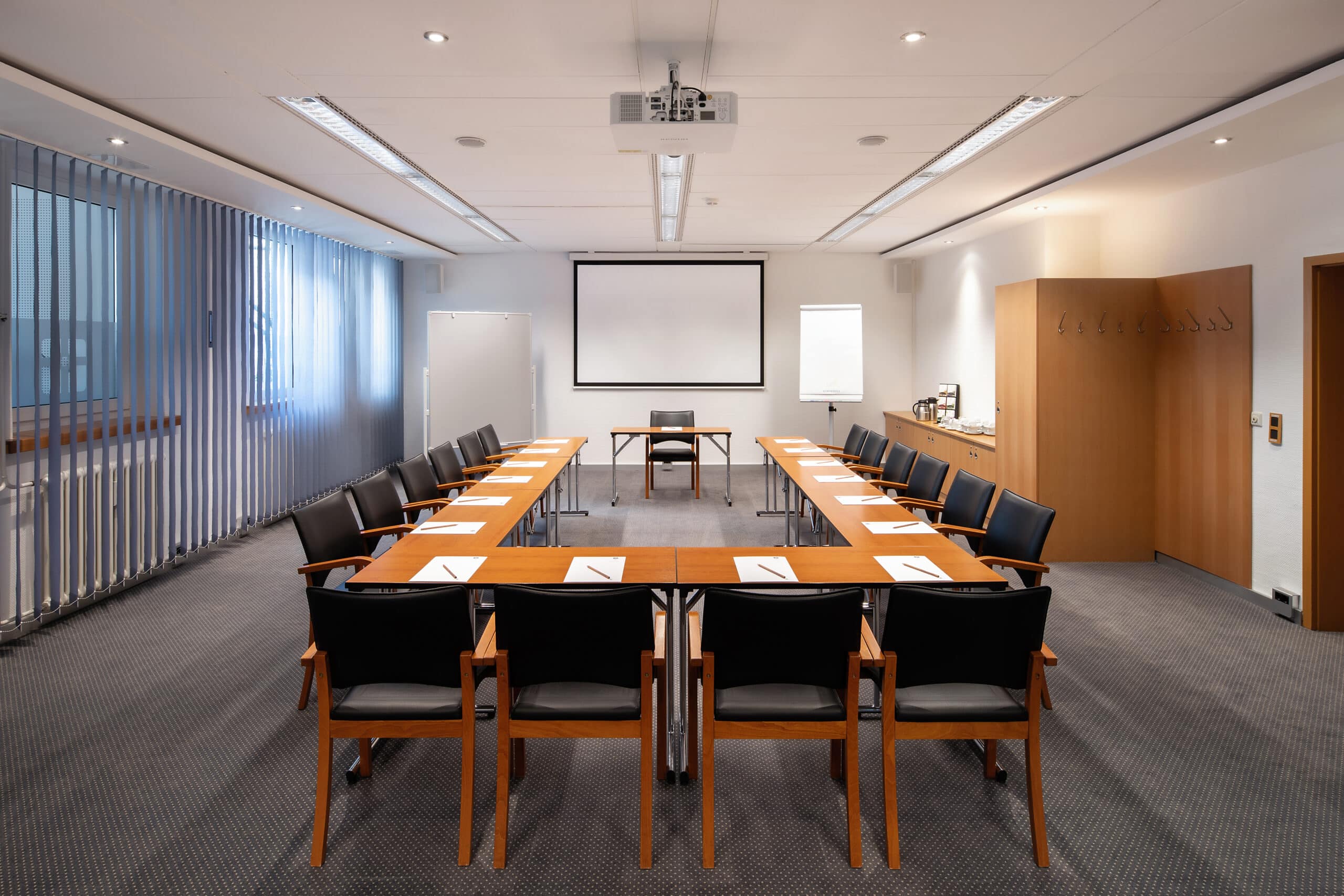 Konferenzraum mit einem großen Tisch, Stühlen und Präsentationstechnik im Hotel Dietrich Bonhoeffer Haus.