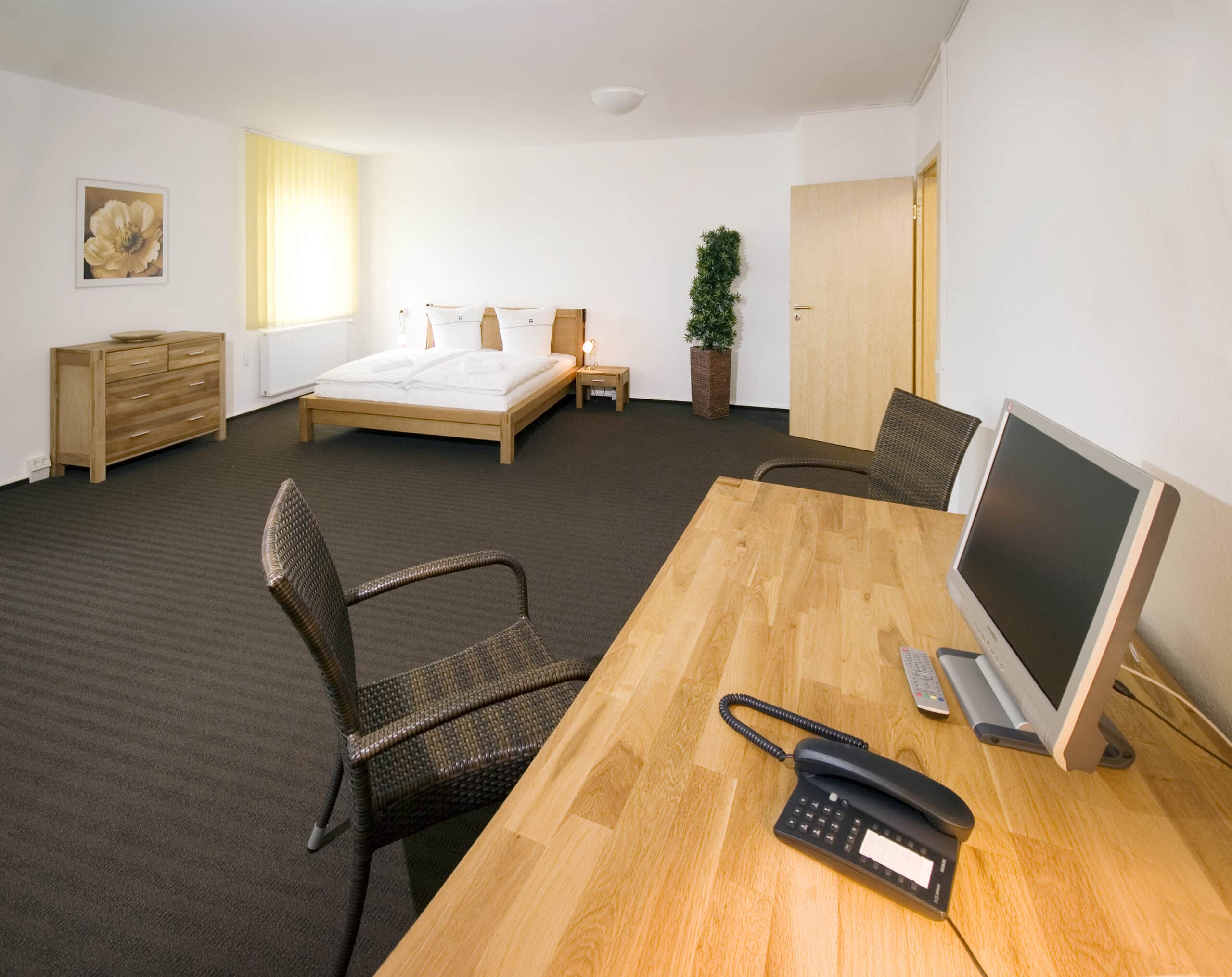 Doppelzimmer im Hotel Dietrich Bonhoeffer Haus mit einem Bett, Schreibtisch und modernen Möbeln.