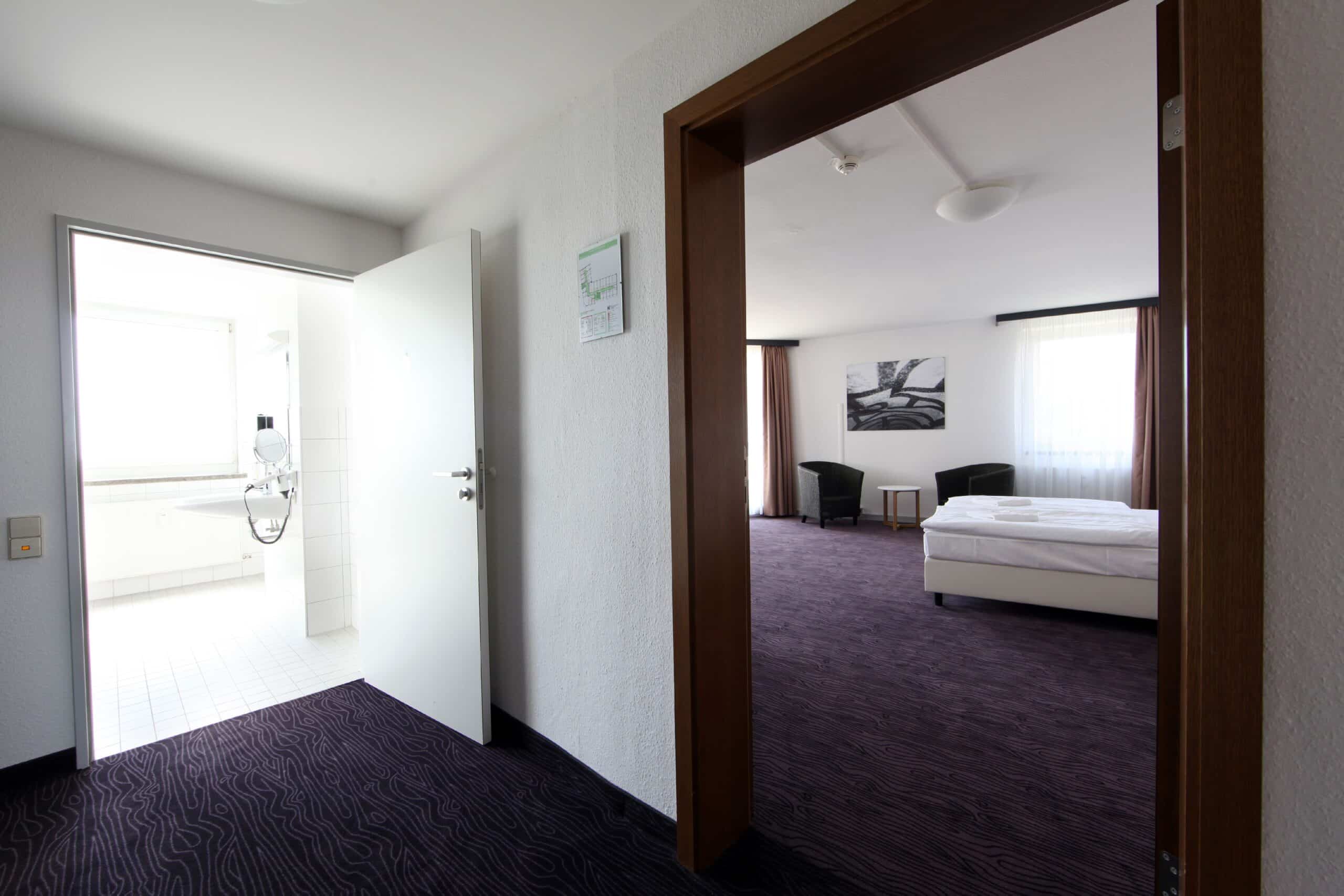 Barrierefreies Doppelzimmer im Hotel Dietrich Bonhoeffer Haus mit zwei Betten und einem Zugang zum Badezimmer.