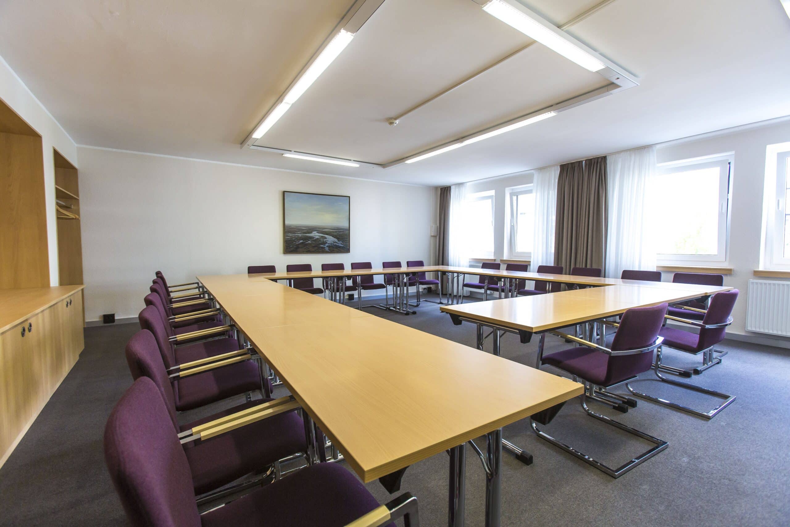 Tagungsraum im Hotel Dietrich Bonhoeffer Haus mit langen Tischen und Stühlen in lila.