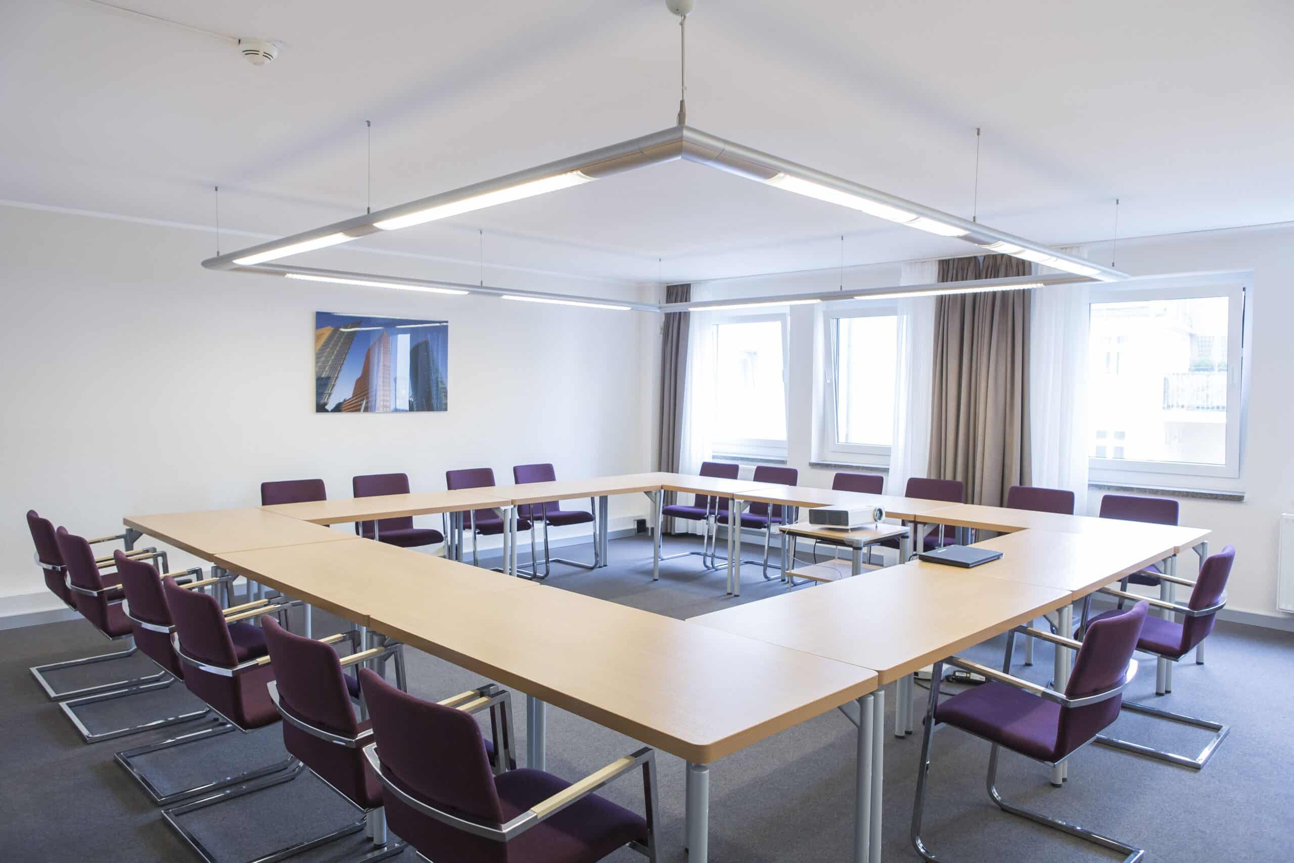 Tagungsraum im Hotel Dietrich Bonhoeffer Haus mit rechteckigem Tisch und Stühlen.