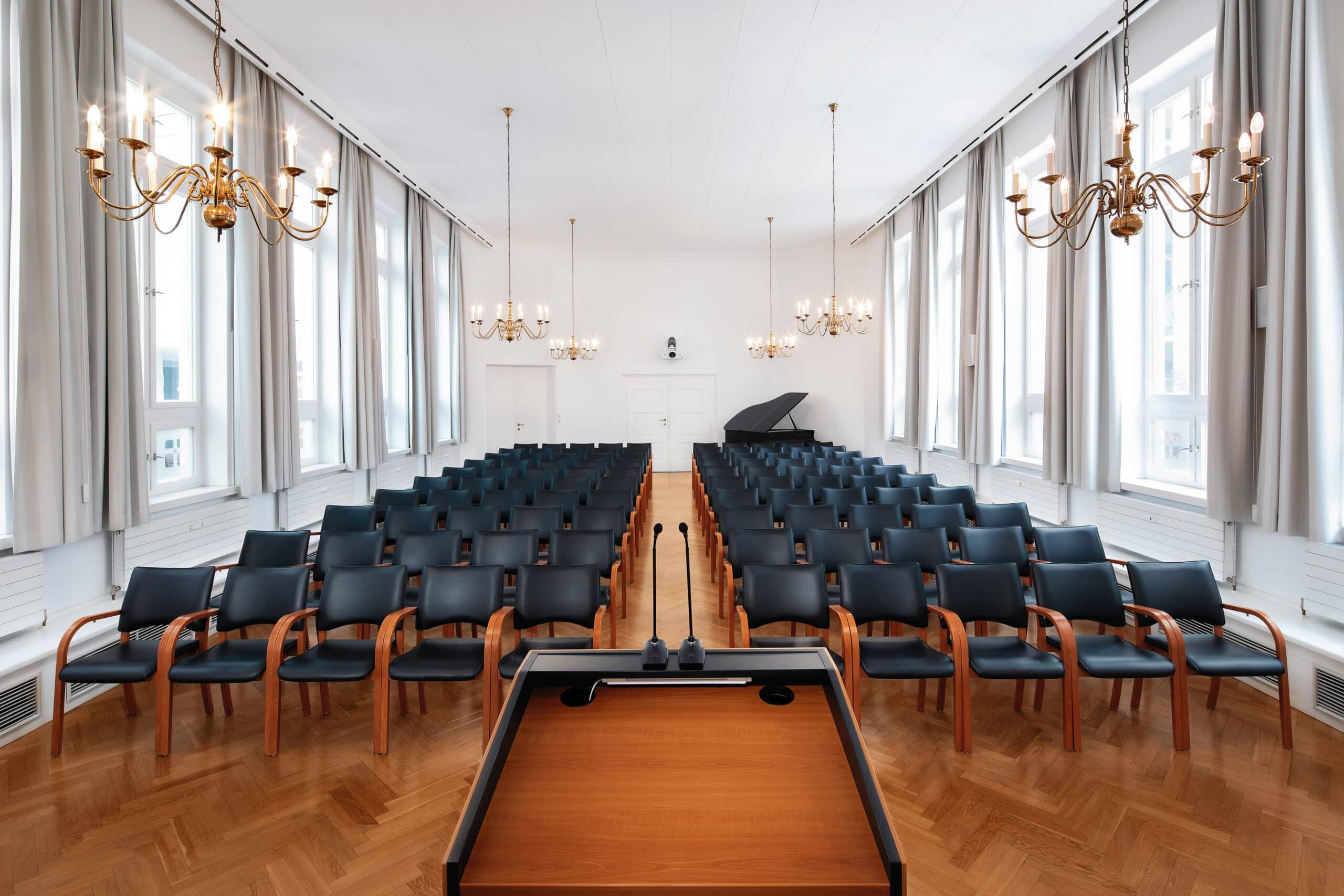 Innenansicht eines Kirchensaals mit Stuhlreihen und einem Rednerpult im Vordergrund.