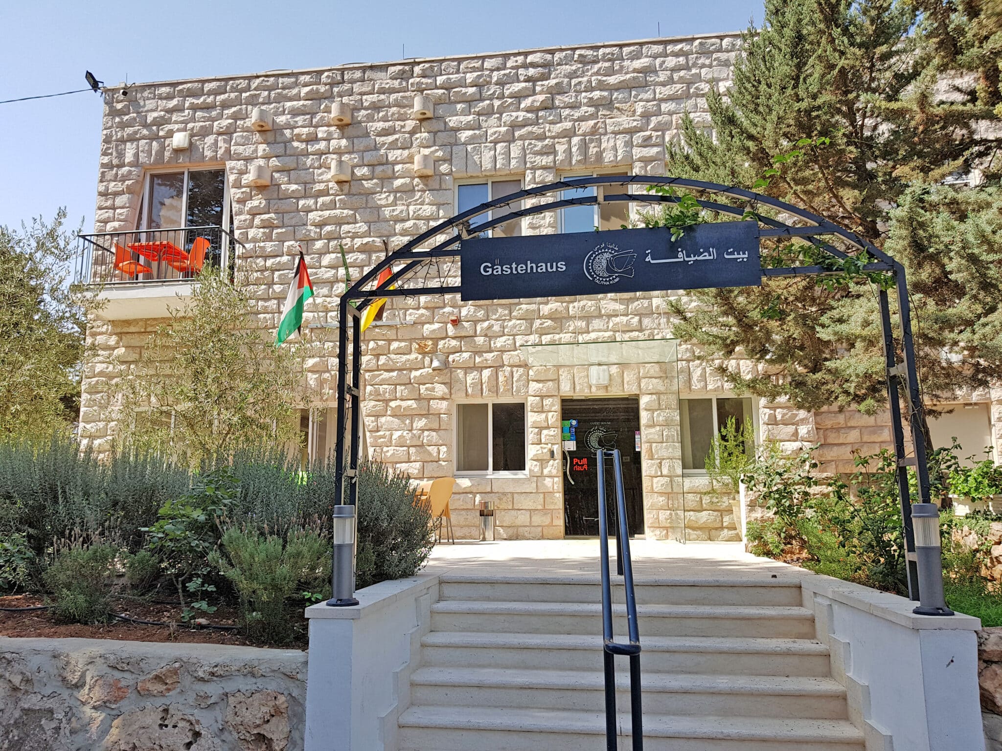 Eingang zum Gastehaus mit Steinfassade und Flaggen in der Nähe von Hotel Dietrich Bonhoeffer Haus.
