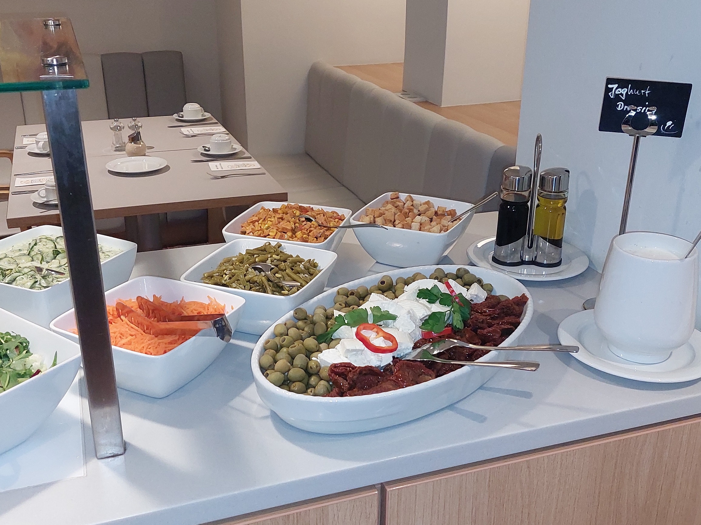 Ein Buffet mit einer Auswahl an verschiedenen Speisen, darunter Salate, Oliven und Gemüse.