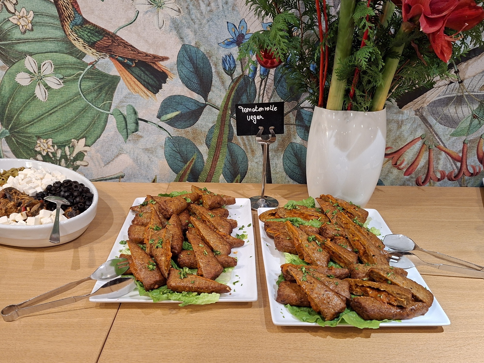Zwei Platten mit verschiedenen vegetarischen Gerichten, angerichtet auf einem Tisch mit frischen Kräutern.