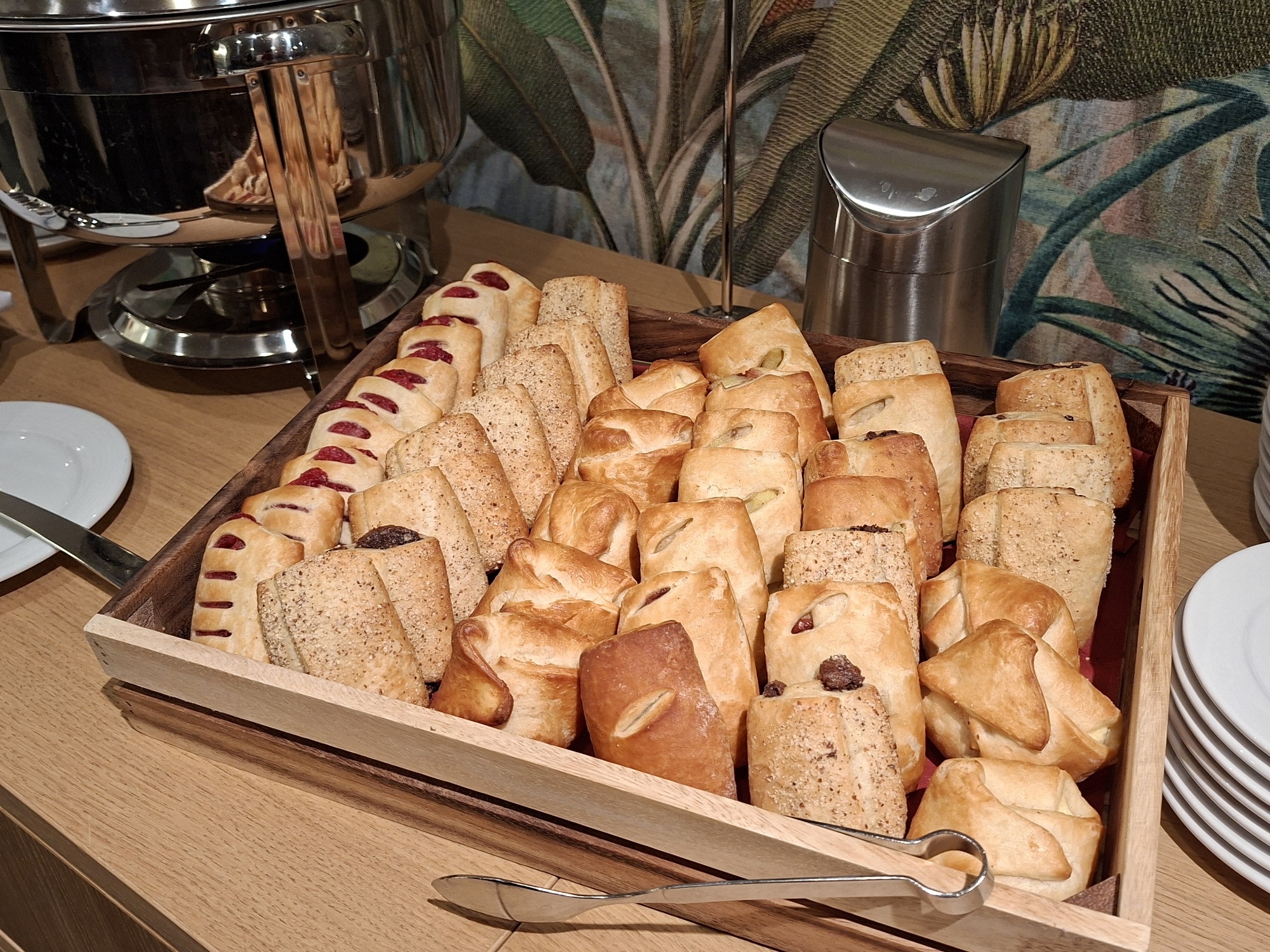 Ein Holztablett mit verschiedenen Brötchen und Gebäck, darunter süße und herzhafte Sorten.